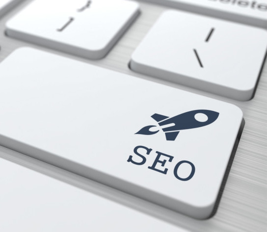 Immagine di dettaglio del tasto Invio di una tastiera bianca per PC. All'interno del tasto al posto della parola "Invio", sulla destra c'è l'icona di colore nero di un piccolo razzo in volo e sotto la parola SEO. 